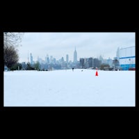 a snow covered field with a city skyline in the background