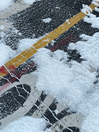 a snow covered street with a red and yellow street sign