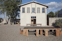 a wooden bench sits in front of a white building